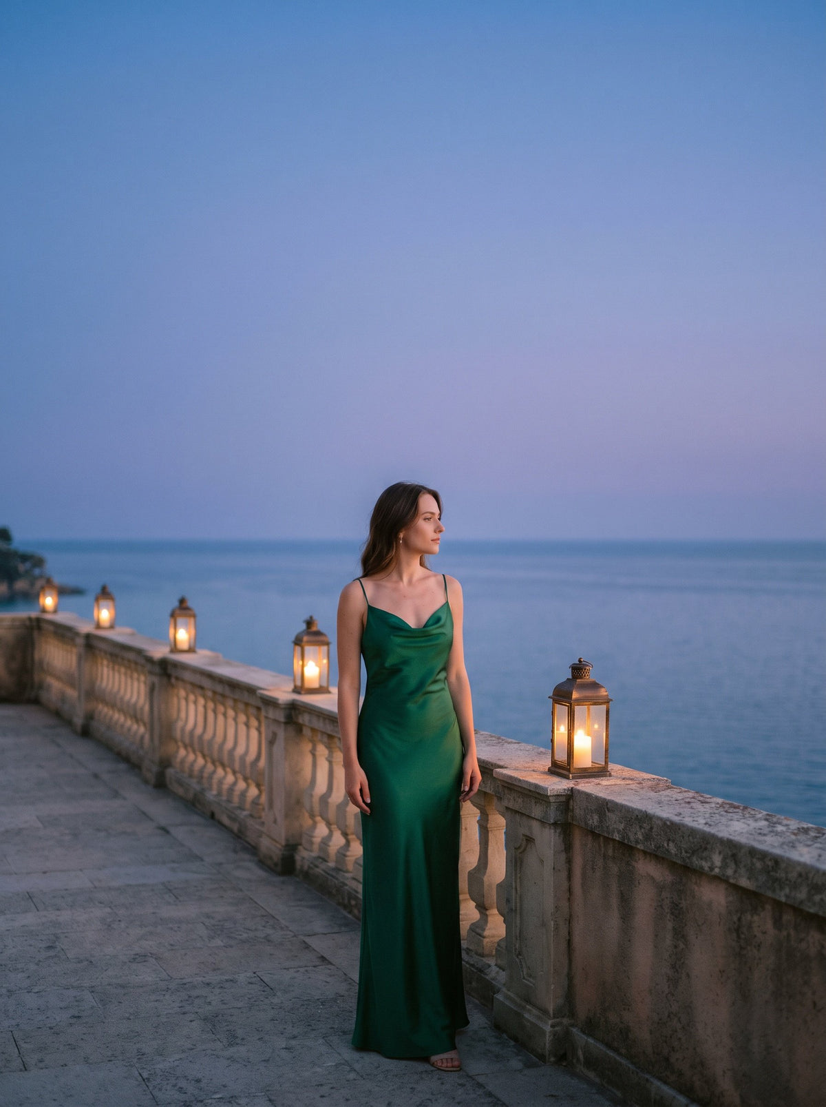 Woman in an emerald satin gown on a seaside terrace at dusk