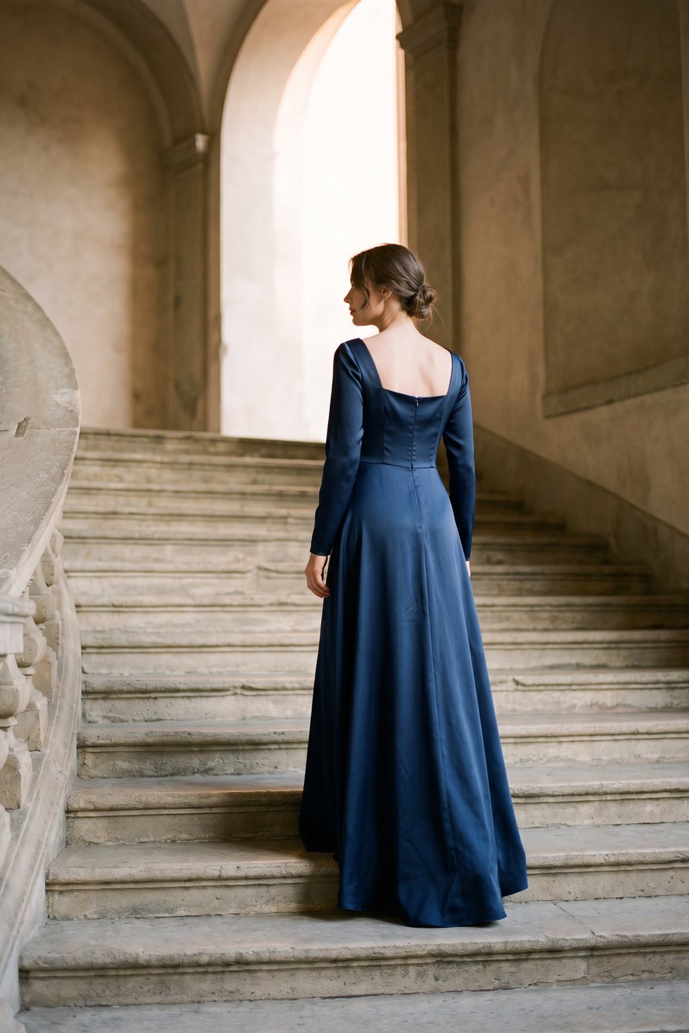 Woman in a navy satin gown on a stone staircase